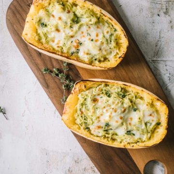 Two spaghetti squash halves on a brown cutting board shot from overhead