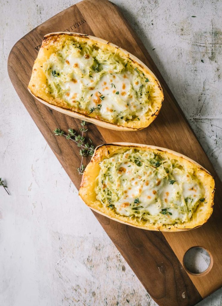 Two spaghetti squash halves on a brown cutting board shot from overhead