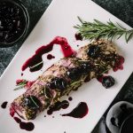Roasted pork tenderloin topped with cherry sauce on a white platter