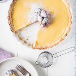 Overhead photo of lemon tart topped with berries with a slice cut out