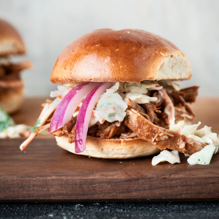 Close up of pulled pork slider topped with pickled red onions