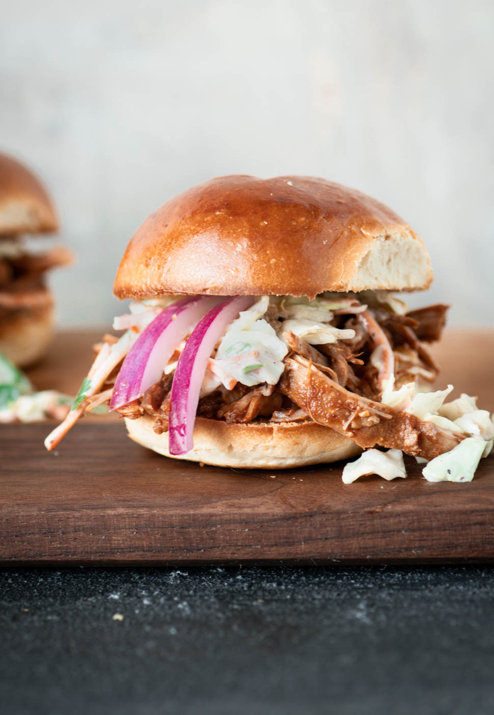 Close up of pulled pork slider topped with pickled red onions