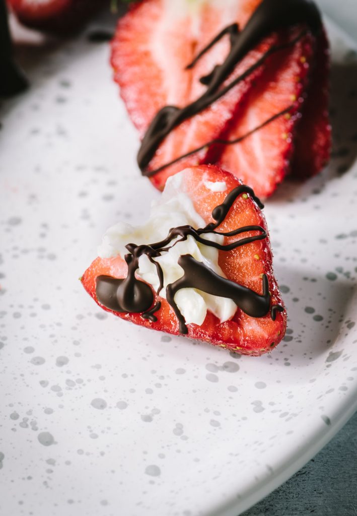 Close of up strawberry half stuffed with cheesecake and drizzled with dark chocolate