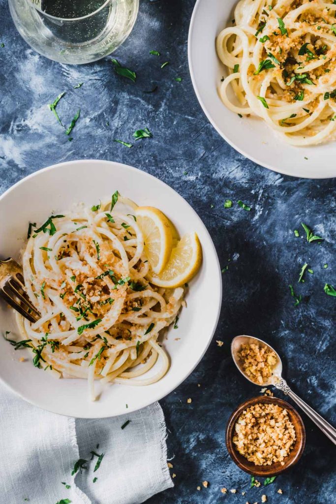 Bucatini in a cream bowl topped with crunchy bread crumbs and a cream lemon sauce