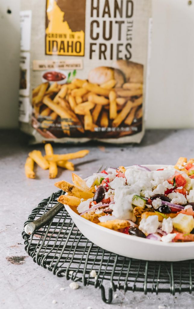 Oven baked fries topped with marinated tomatoes, peppers, feta and tzatziki sauce