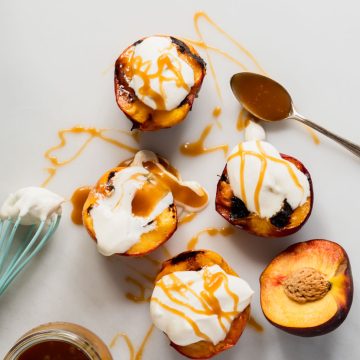 Four grilled peach halves topped with whipped mascarpone and drizzled with caramel sauce