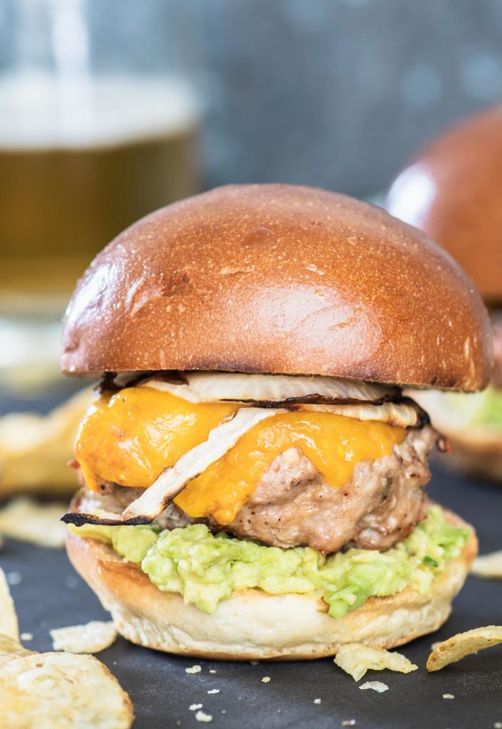 Close up of a turkey burger slider topped with grilled onions and melted cheddar cheese