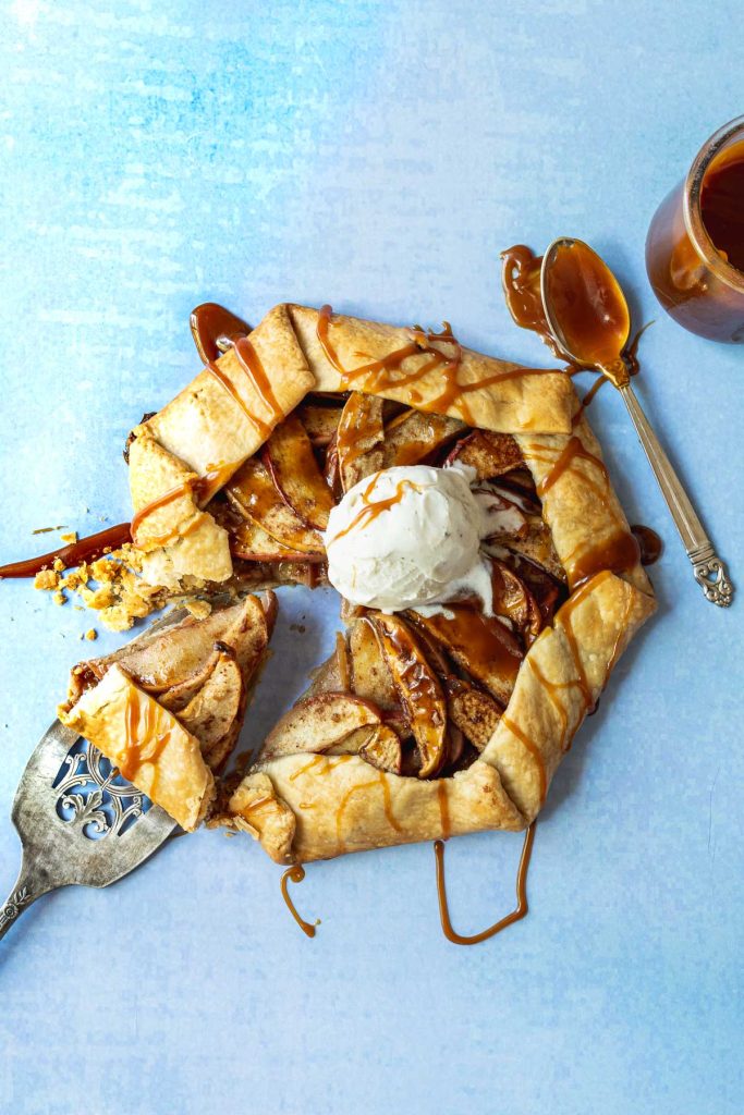 Apple galette topped with vanilla ice cream scoop on a light blue background