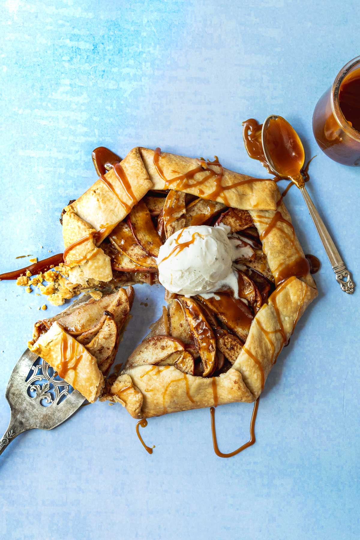 Apple galette topped with vanilla ice cream scoop on a light blue background