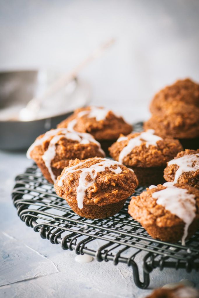 Six mini pumpkin muffins on a black wire rack.