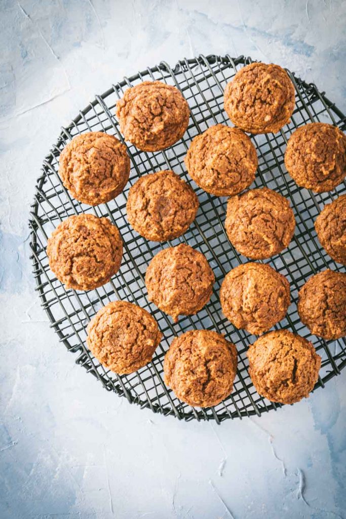 Pumpkin muffins on a round black cooling rack.