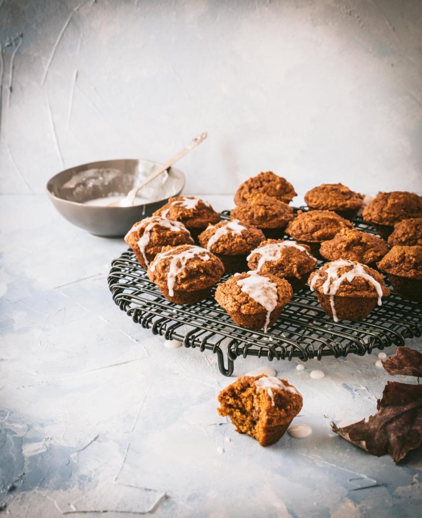 Glazed pumpkin muffins on a black wire rack. 