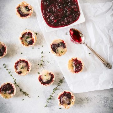 Cranberry brie tarts with a dish of cranberry sauce shot from overhead