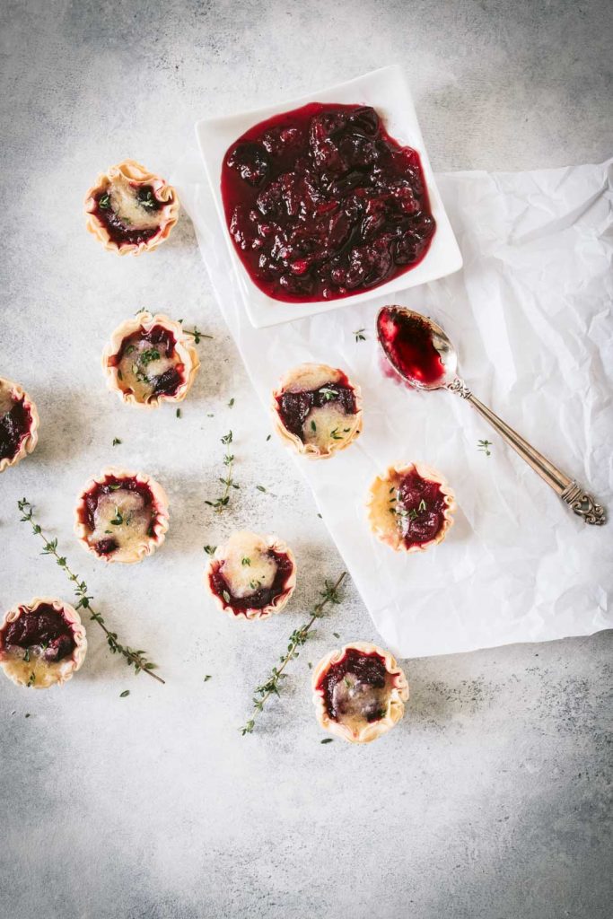 Cranberry brie tarts with a dish of cranberry sauce shot from overhead