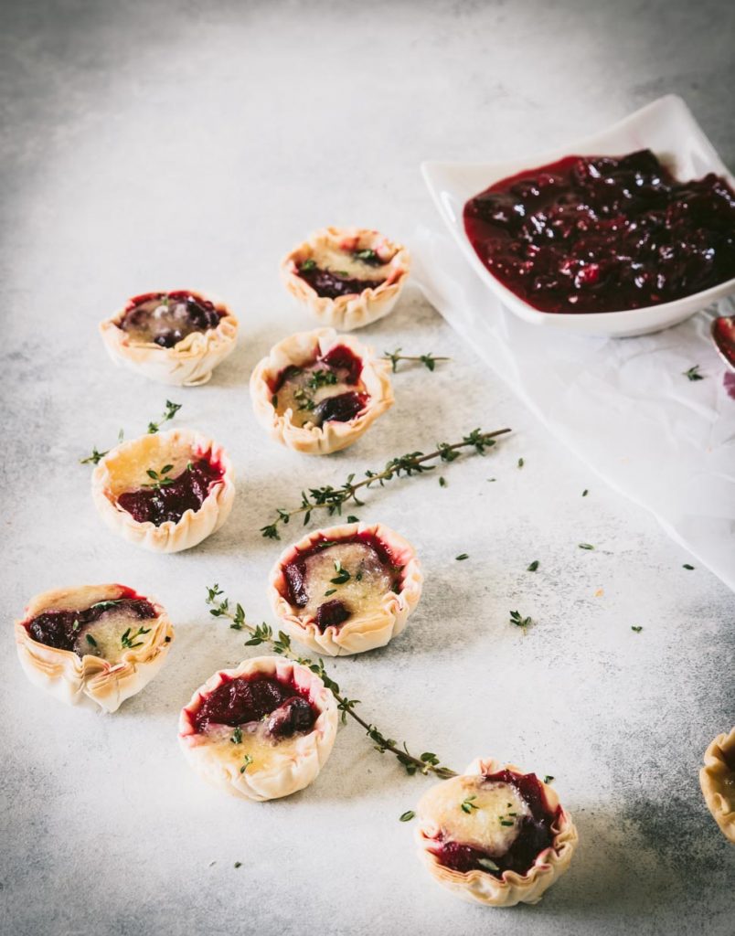 Mini cranberry brie tarts topped with some fresh thyme leaves