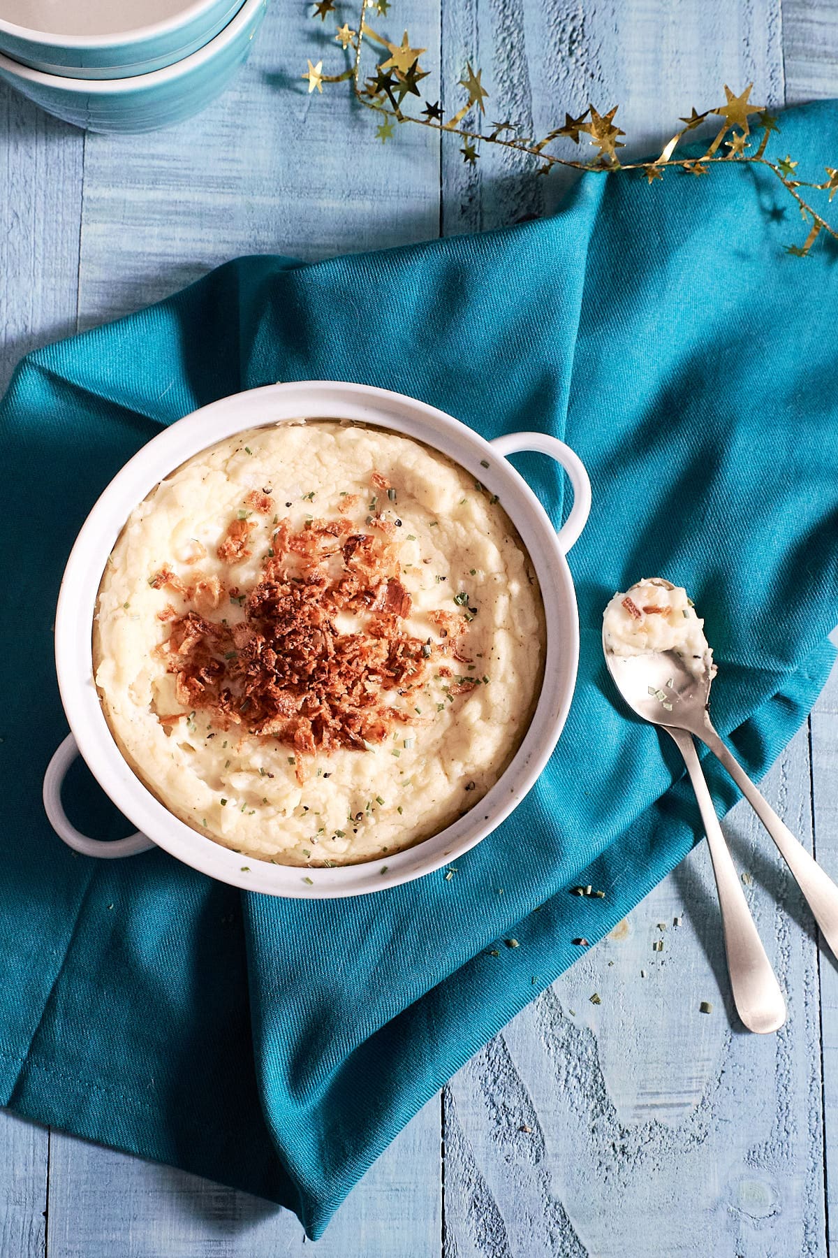 Overhead shot of a serving side filled with mashed potatoes and topped with crispy onions