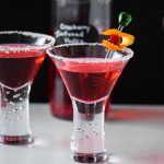 Cranberry Vodka martinis with a bottle of cranberry infused vodka in the background