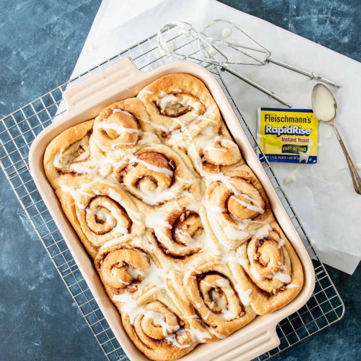 Orange cinnamon rolls in a baking pan drizzled with glaze