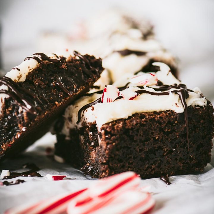 Close up of brownies topped with cream cheese frosting and candy cane bits