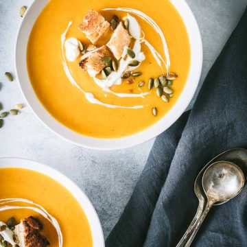 Overhead shot of two white bowls filled with butternut squash soup