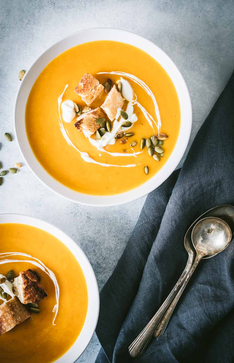Overhead shot of two white bowls filled with butternut squash soup