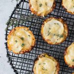 Overhead shot of individual potato gratins on a black wire cooling rack