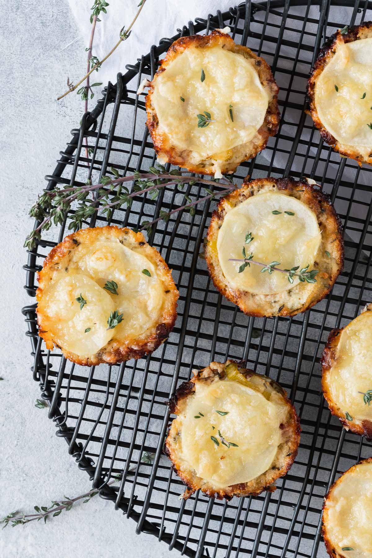 Overhead shot of individual potato gratins on a black wire cooling rack