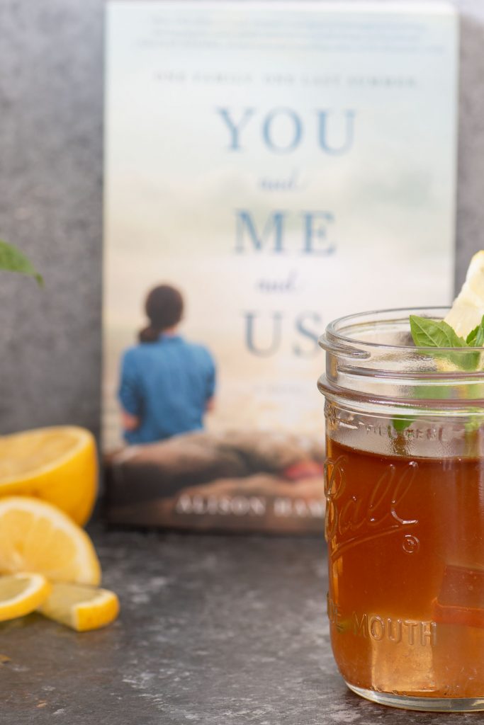 Bourbon Arnold Palmer with basil leaf garnish in front of book