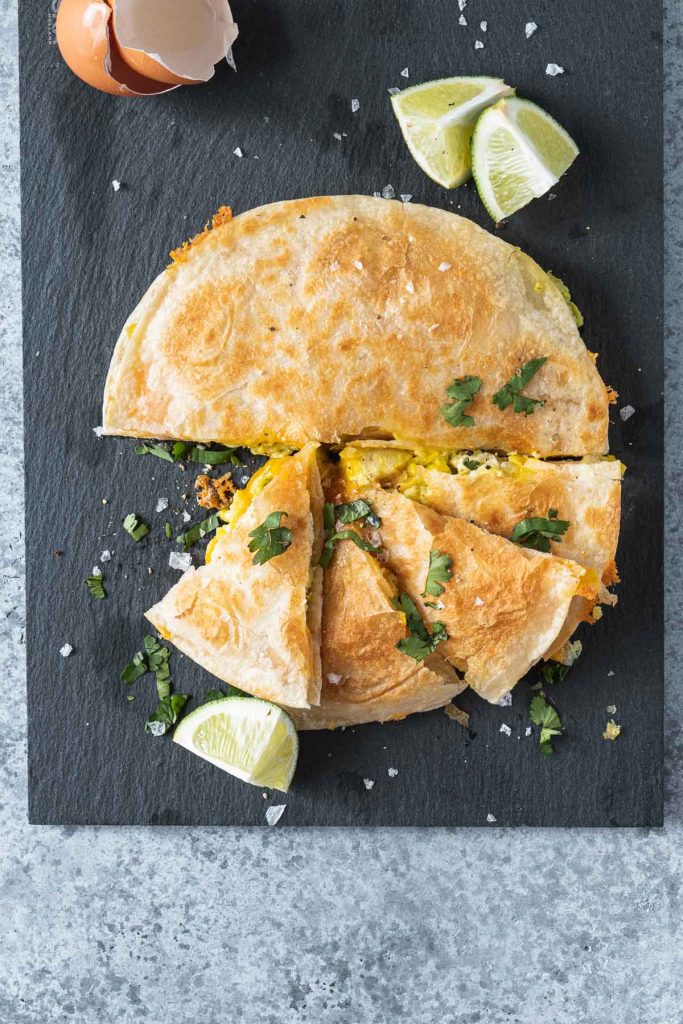 Breakfast quesadilla on a black slate board shot from overhead