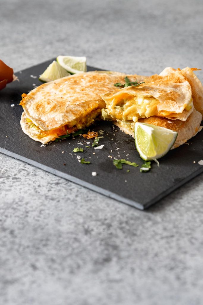 Quesadilla with eggs and avocado, sliced, on a slate board