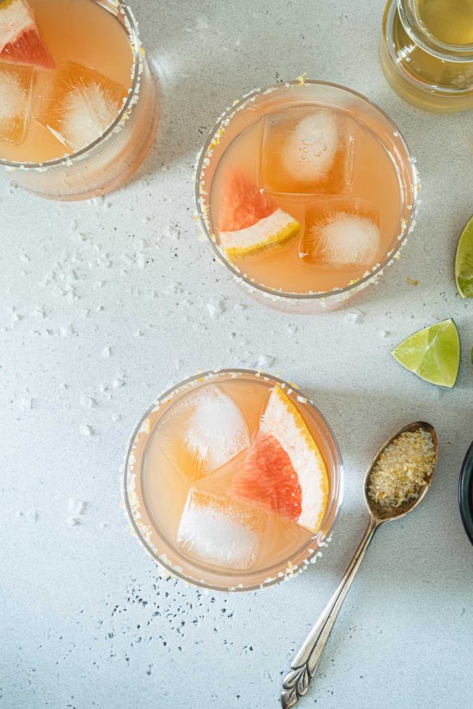 Overhead shot of three grapefruit margaritas in salt rimmed glasses