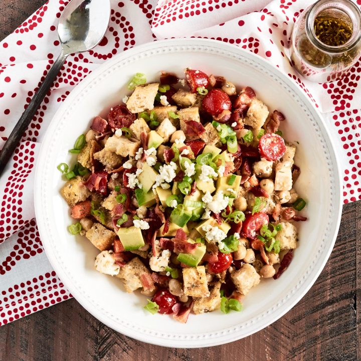 Overhead shot of a white bowl filled with toasted bread cubes and veggies