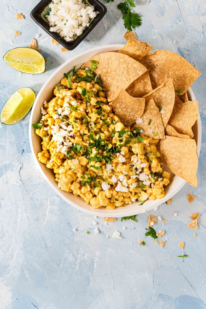 Overhead shot of Mexican Street Corn dip in a white bowl with tortilla chips