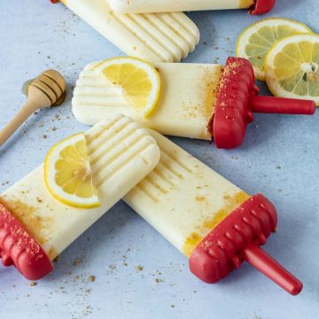 Close up of lemon popsicles with red sticks on a light blue background