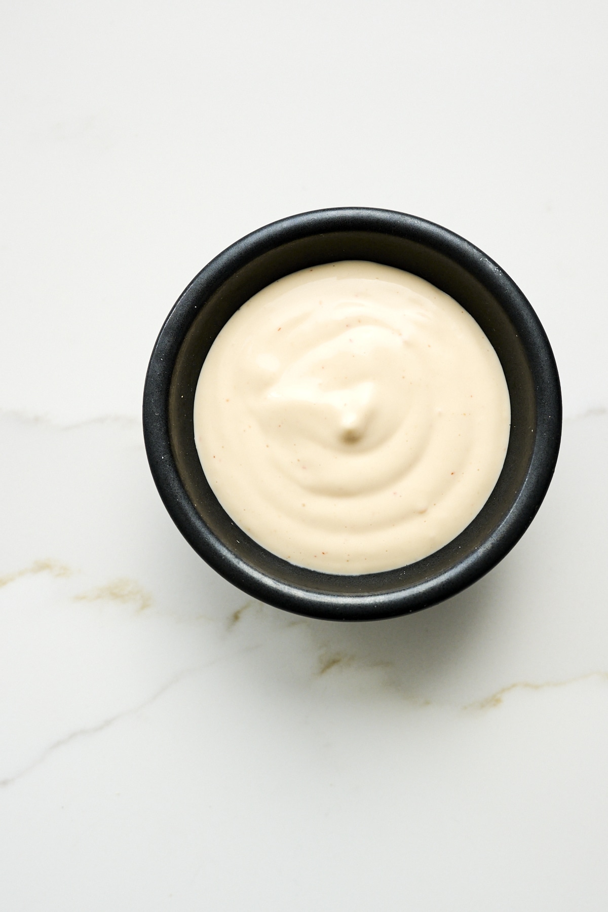 Mayo based sauce in a black bowl