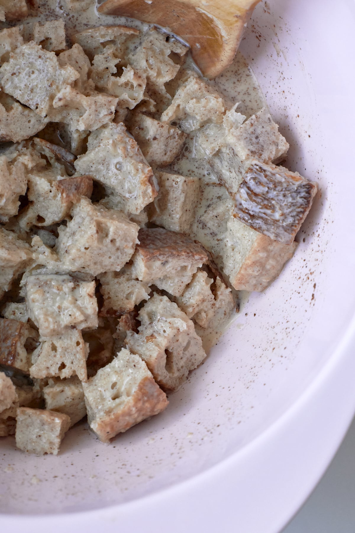Bread cubes soaking in eggnog french toast mixture