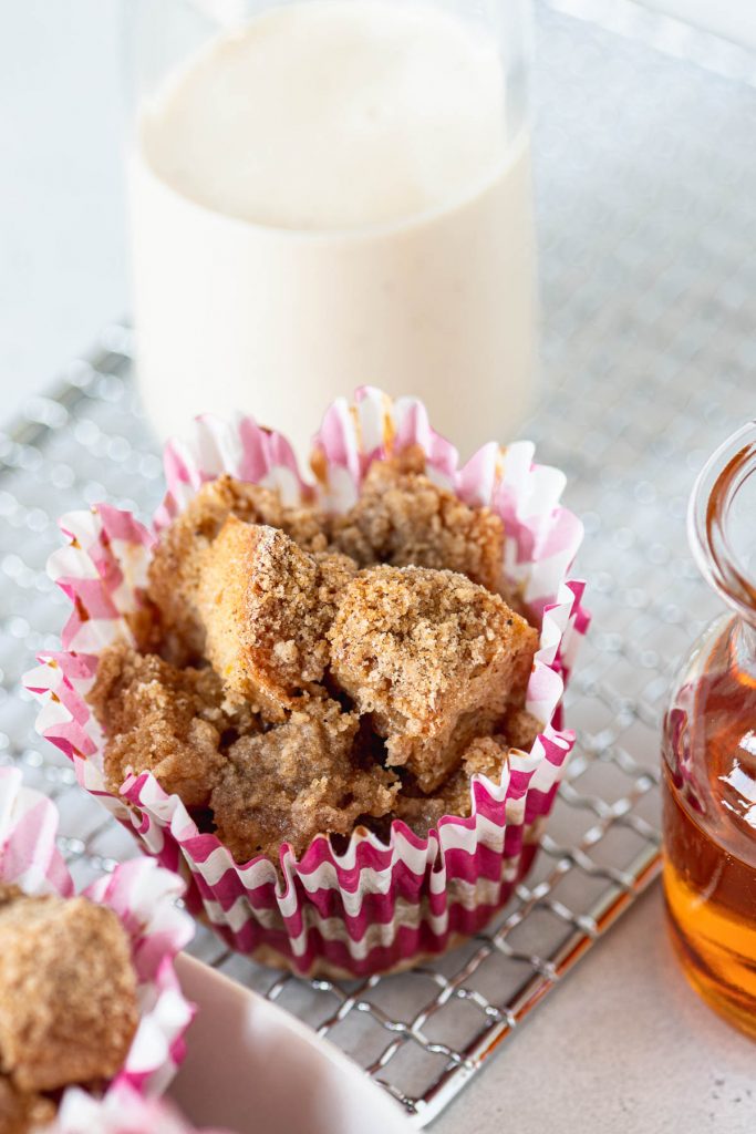 Close up of one french toast muffin on a wire cooling rack with a glass of eggnog in the background