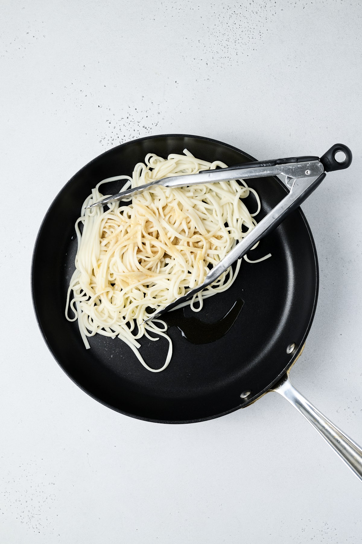 Udon noodles in a pan being tossed with miso sauce