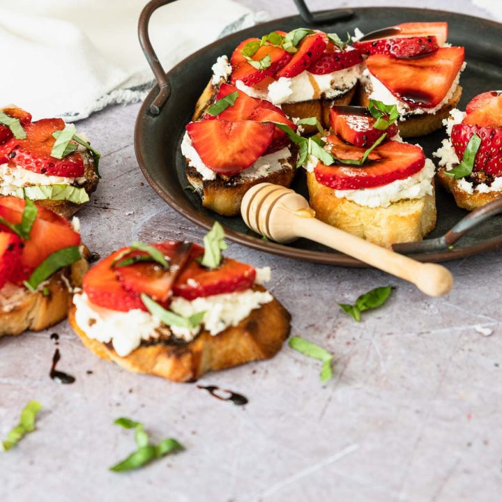 Crostini topped with sliced strawberries, goat cheese, basil and balsamic glaze