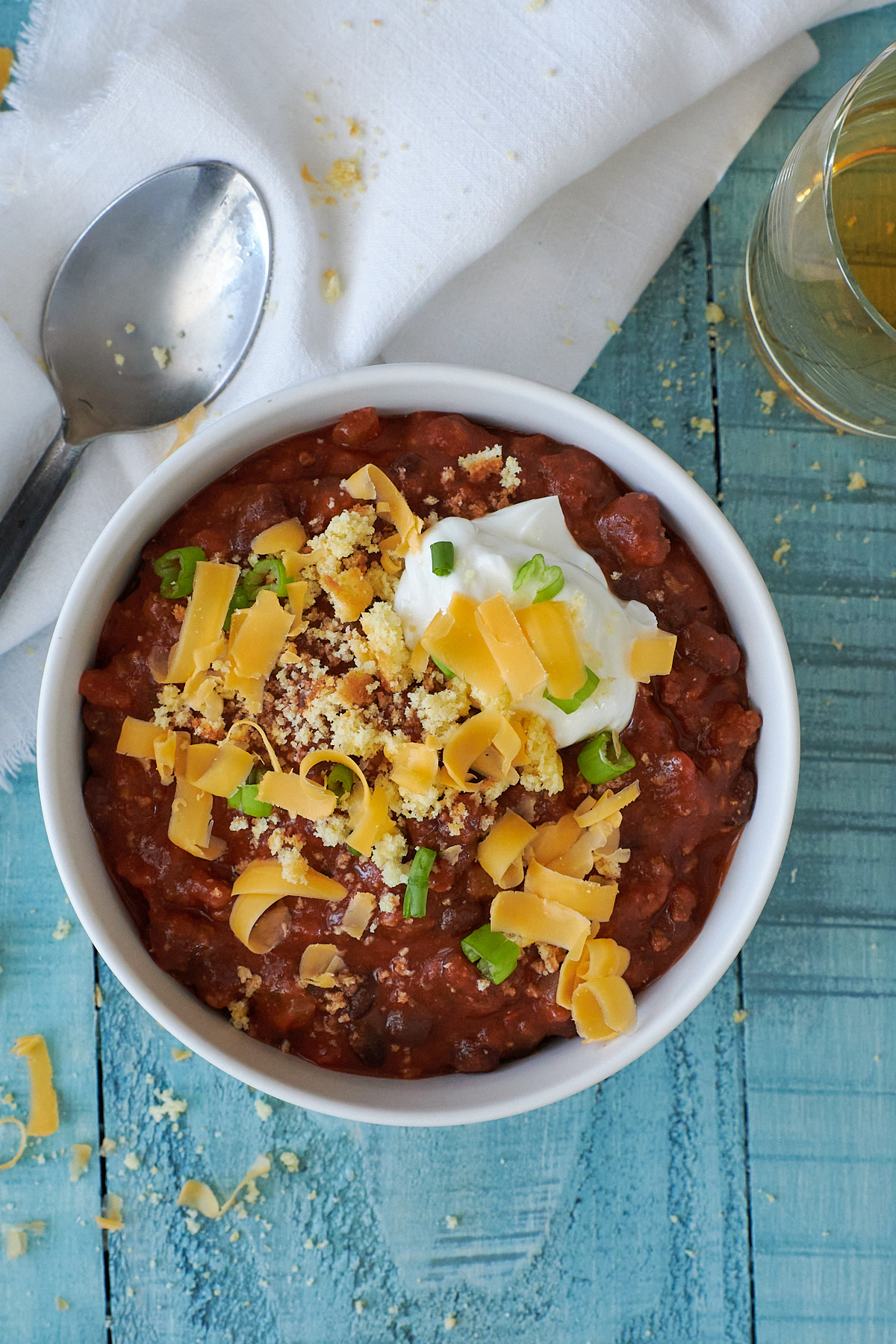 Overhead shot of a bowl of turkey chili topped with shredded cheese, green onions and greek yogurt