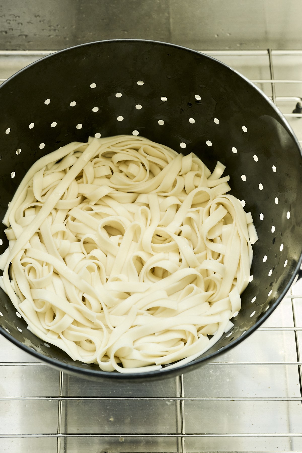 Cooked Udon noodles in a black strainer