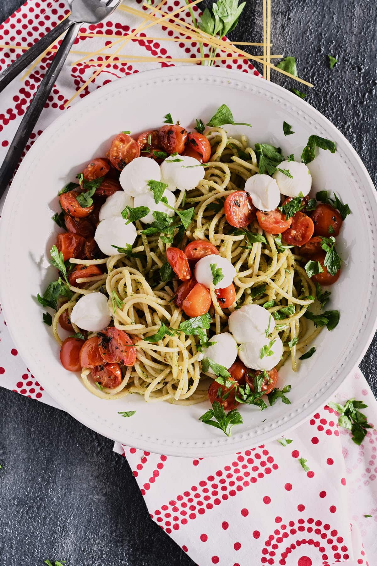 Overhead shot of spaghetti topped with roasted tomatoes and fresh mozzarella