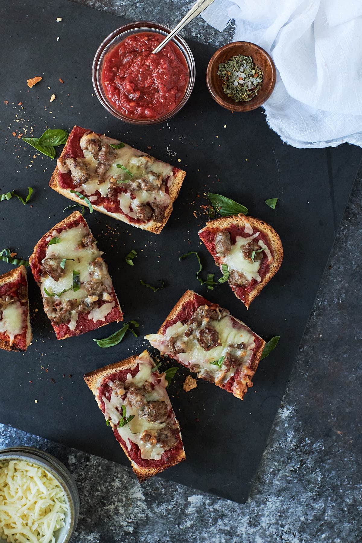 Overhead shot of slices of french bread topped with pizza sauce, cheese and sausage