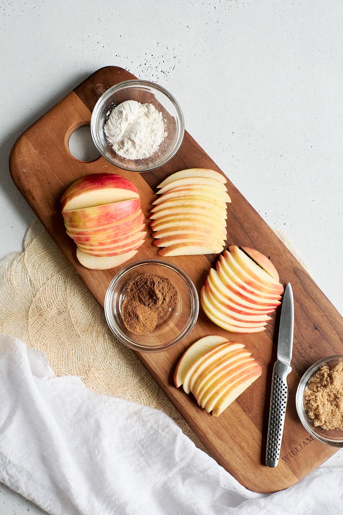 Sliced apples and filling ingredients on a brown cutting board