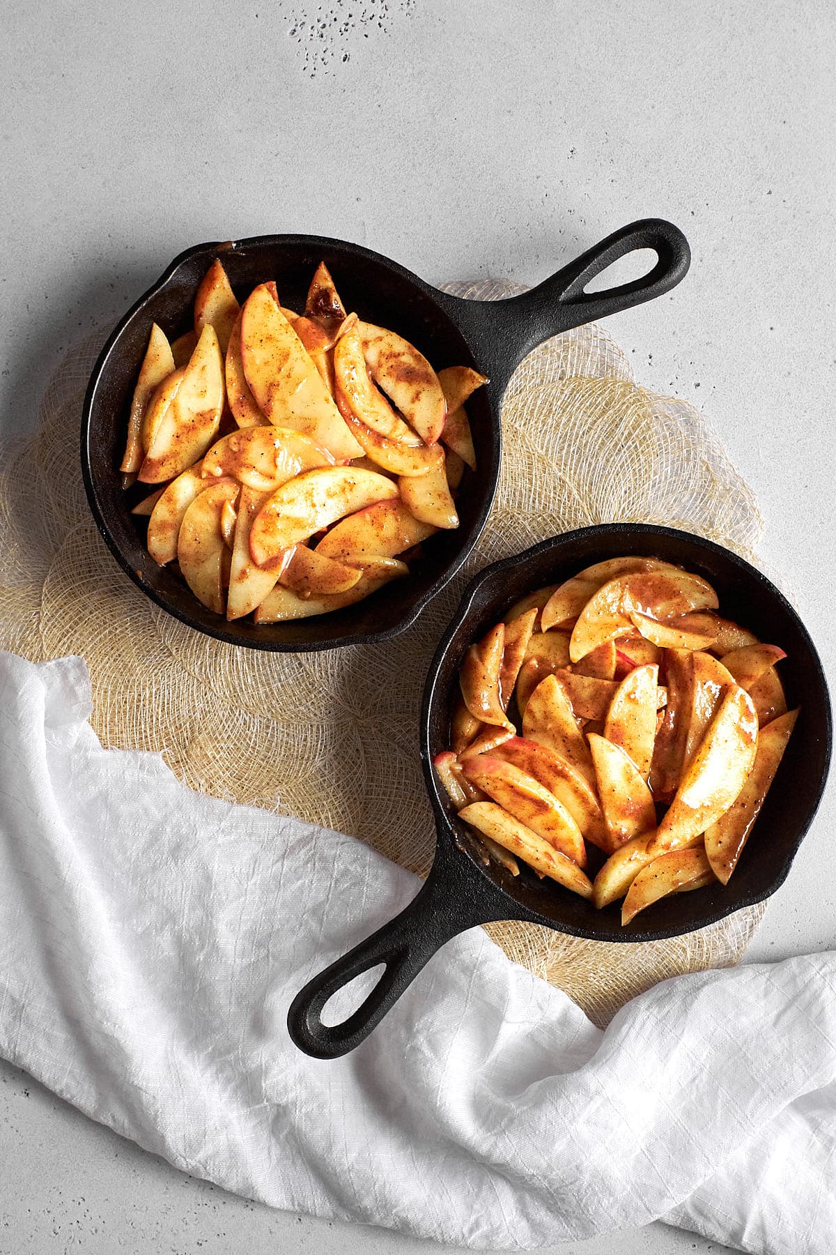 Two small cast iron skillets with apple crisp filling