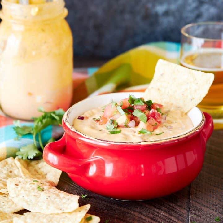 Queso dip in a red bowl topped with pico de gallo