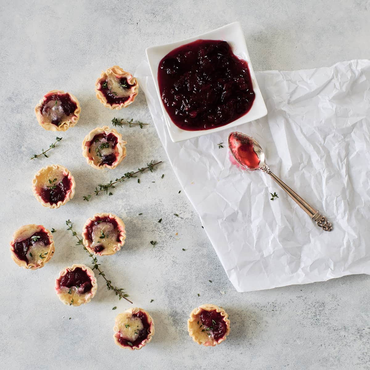 Nine mini cranberry brie tarts on a light background