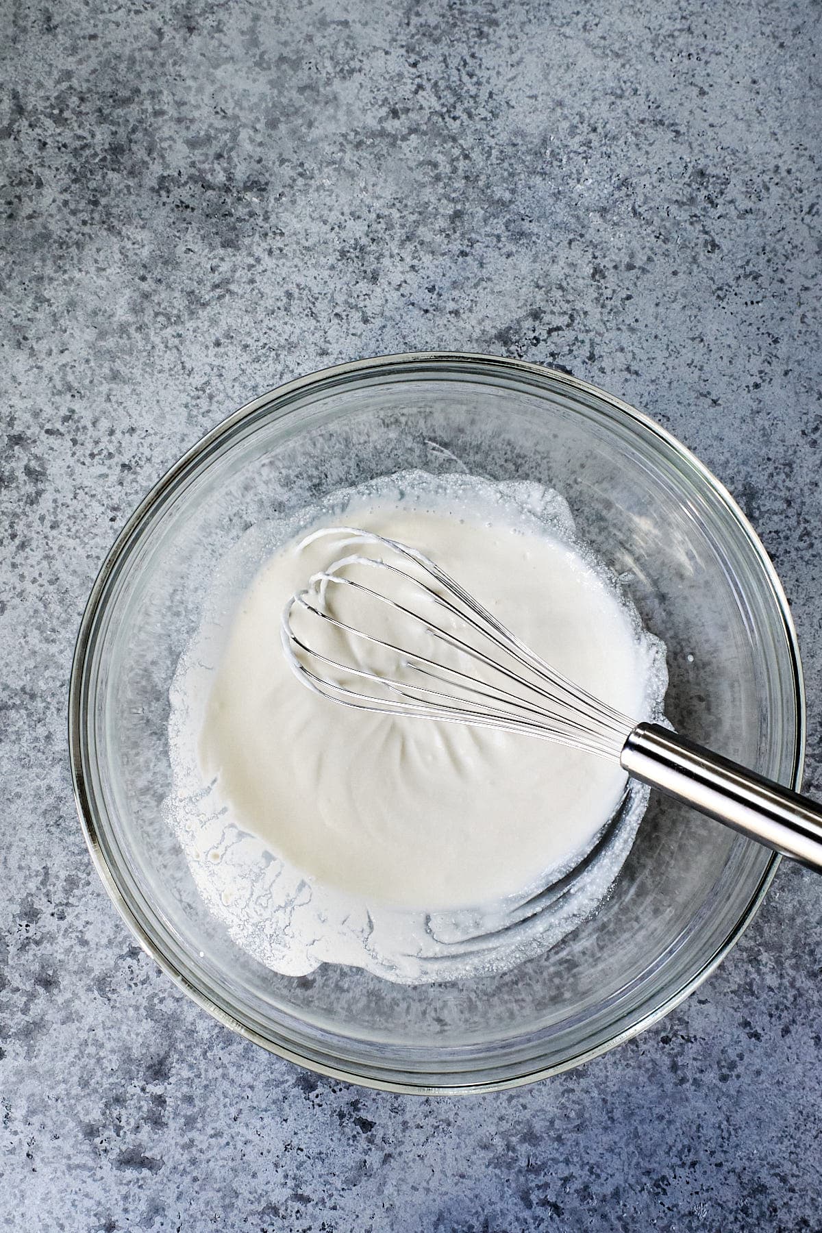 Ricotta and egg whites being whisked in a glass bowl