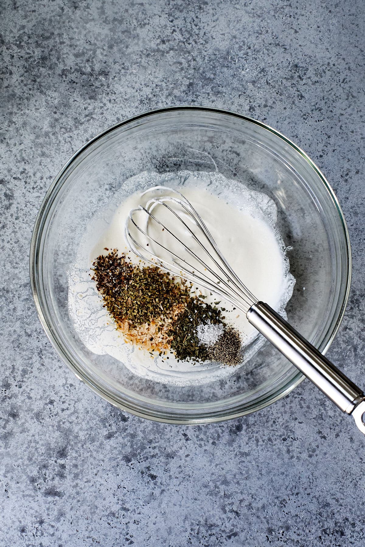 Ricotta being whisked with seasonings in a glass bowl