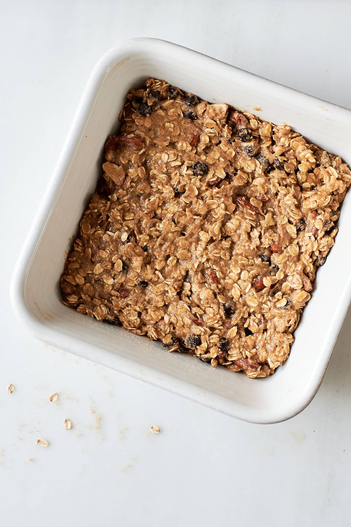 Chocolate chip oatmeal bar batter in a white baking pan